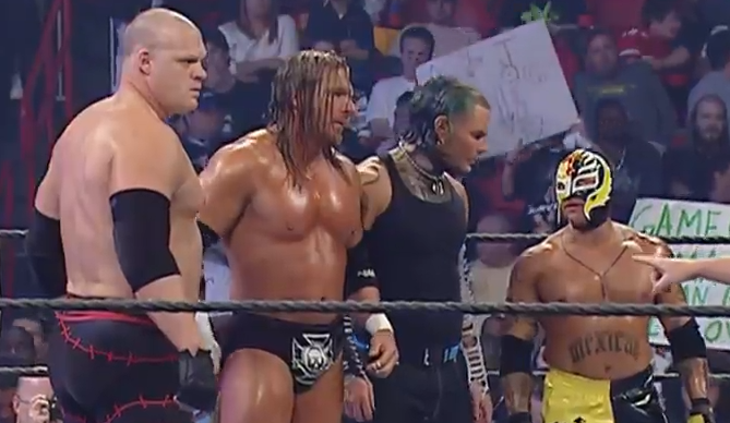 Kane, Triple H, Jeff Hardy, and Rey Mysterio stand on one side of the ring.