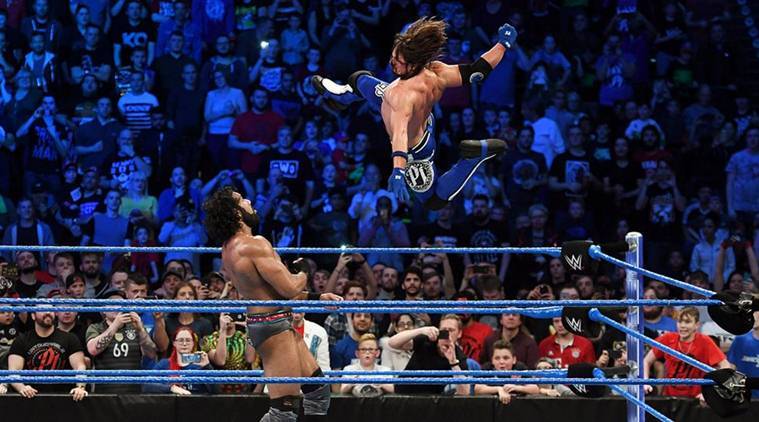 AJ Styles in mid-air, about to deliver a Phenomenal Forearm onto Jinder Mahal. 