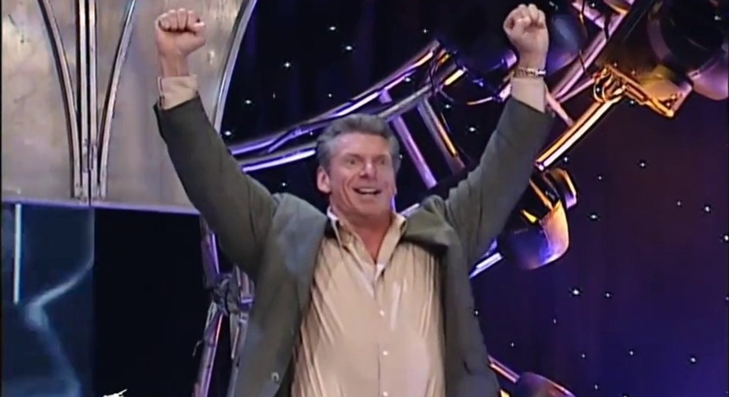 Vince, with a wild-eyed expression and smile, holds his hands in the air in victory.
