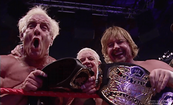 Ric Flair and Roddy Piper celebrates with their tag team title belts.
