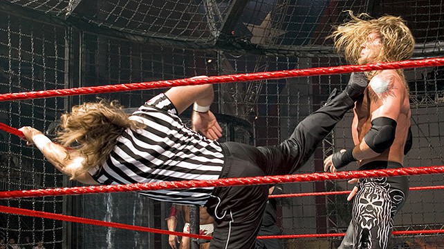 Shawn Michaels, in his referee attire, delivers a Sweet Chin Music to Edge.
